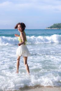 Full length of young woman standing at beach