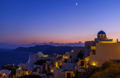 Illuminated santorini by mountains against clear sky at sunset