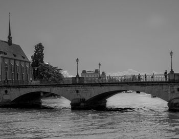 Bridge over river by buildings against clear sky
