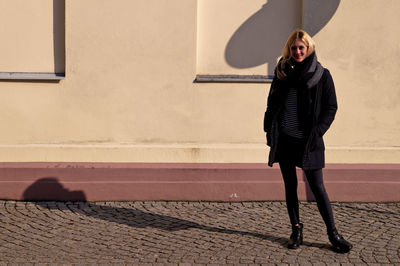 Full length of young woman standing on footpath