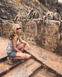 Portrait of woman crouching against monkeys on railing