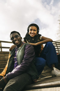 Smiling male and female friends wearing casuals while sitting on steps
