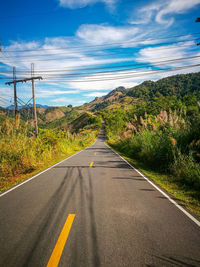 Road leading towards mountain against sky