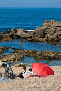 Deck chairs on rocks by sea against sky