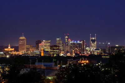 Illuminated buildings in city against sky at night