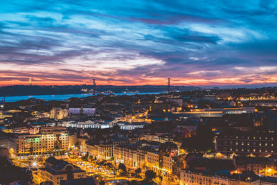 Aerial view of illuminated buildings against cloudy sky during sunset