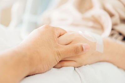 Close-up of woman hand on bed