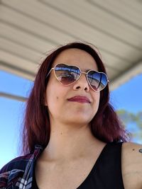 Low angle view of young woman wearing sunglasses looking away 