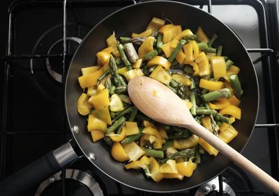 Directly above shot of asparagus and yellow bell pepper cooking in pan on stove