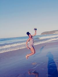 Man jumping on beach against clear sky