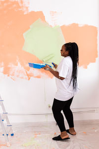 Full length of woman standing against wall