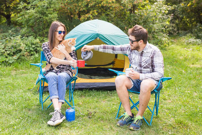 Young couple sitting on grass against trees