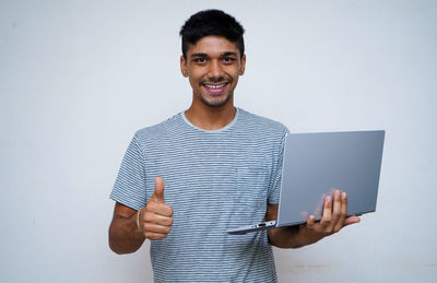 Portrait of smiling young man standing against white background