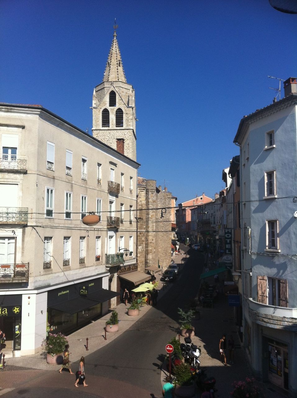 building exterior, architecture, built structure, clear sky, city, blue, church, car, street, transportation, incidental people, religion, land vehicle, mode of transport, city life, road, sunlight, residential building, travel destinations