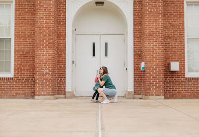 Young millennial mother sending daughter off back to school