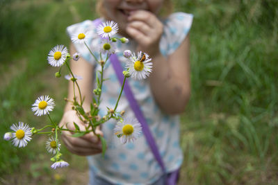 Midsection of girl holding ladybug on flowering plant