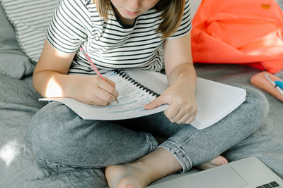 Midsection of woman reading book at home