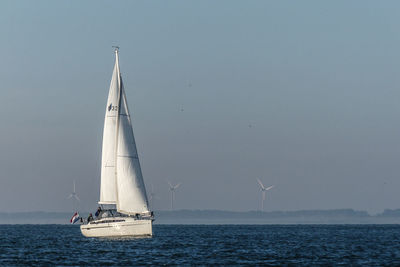 Sailboat sailing on sea against clear sky