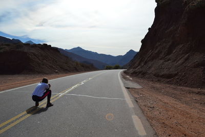 Rear view of woman on road against sky