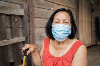 Portrait senior woman wearing mask sitting outdoors