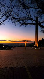 Footpath by street against sky during sunset