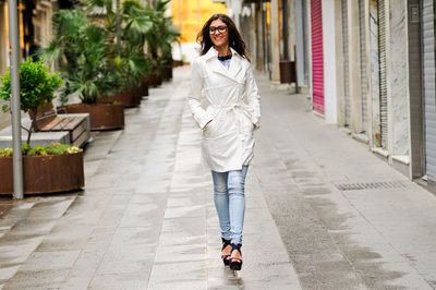 Cheerful young woman walking on footpath in city