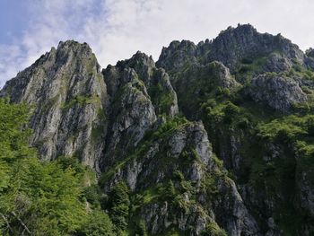 Low angle view of rocks and mountains against sky