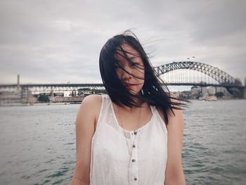 Portrait of young woman standing against river