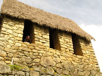 Tourist girl posing in an inca window in machu picchu