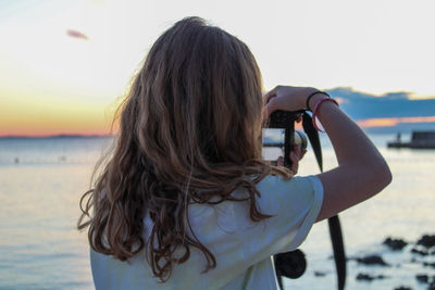 Rear view of woman photographing against sky