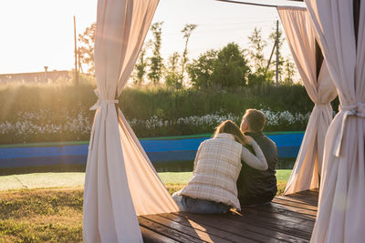 Rear view of man and woman relaxing at tent