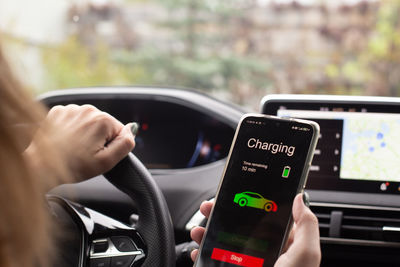 Midsection of man using mobile phone in car