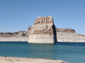 Rock formations on shore against clear blue sky