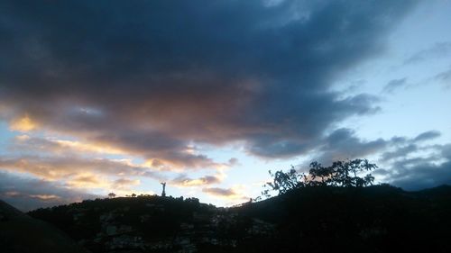 Silhouette of trees against cloudy sky