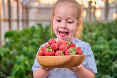 Portrait of cute girl holding strawberries