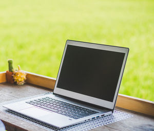 Close-up of laptop on table by window