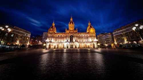 Square in a coruña with the illuminated palacio municipal during dusk with high flying clouds.