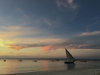 Sailboat in sea against sky during sunset