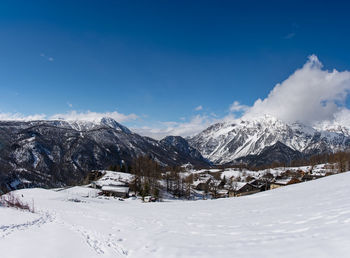 Scenic view of snowcapped mountains against blue sky