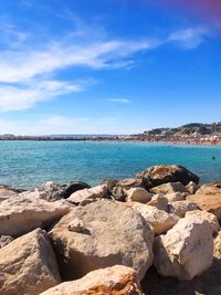Rocks by sea against blue sky