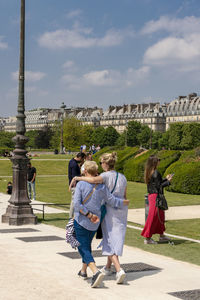 Rear view of people walking against built structure