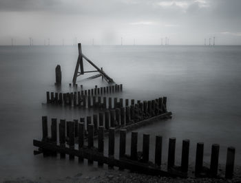 High angle view of wooden posts in sea during foggy weather