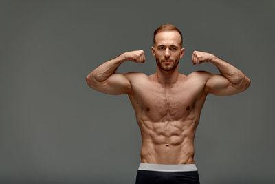 Shirtless muscular man exercising against black background