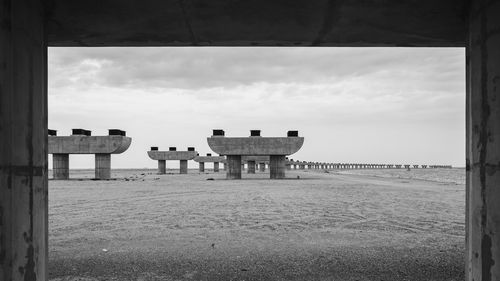 Empty benches on beach against sky