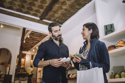 Salesman and female customer discussing over shoe in clothing store