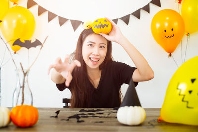 Portrait of smiling young woman with balloons at table