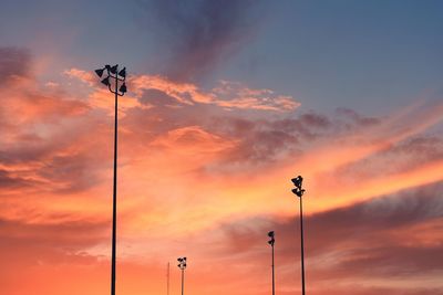 Low angle view of street lights against orange sky