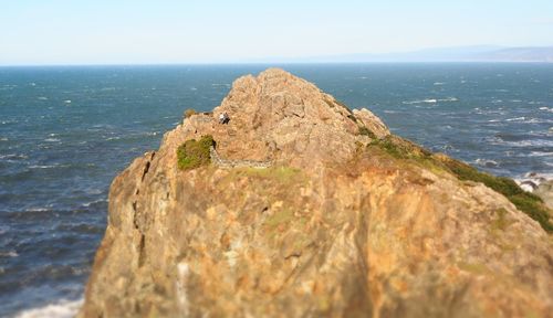 Scenic view of cliff by sea against sky