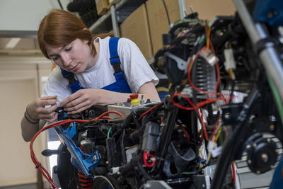 Female technician repairing motorcycle at workshop