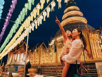 Woman standing against illuminated building at night